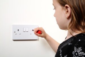 child putting something into electrical socket